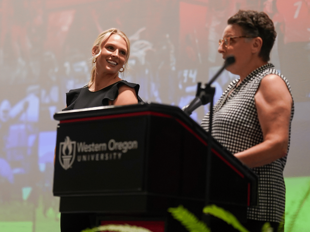 Image of two women on stage speaking to a group at an athletic auction
